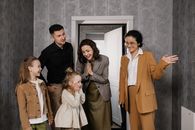 A joyful family is warmly welcomed by a realtor inside a modern home.