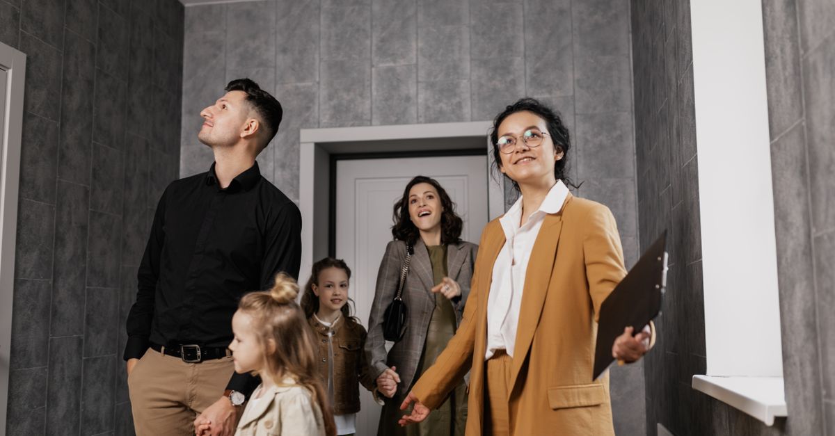 Happy family exploring a new home with a professional real estate agent guiding the tour.