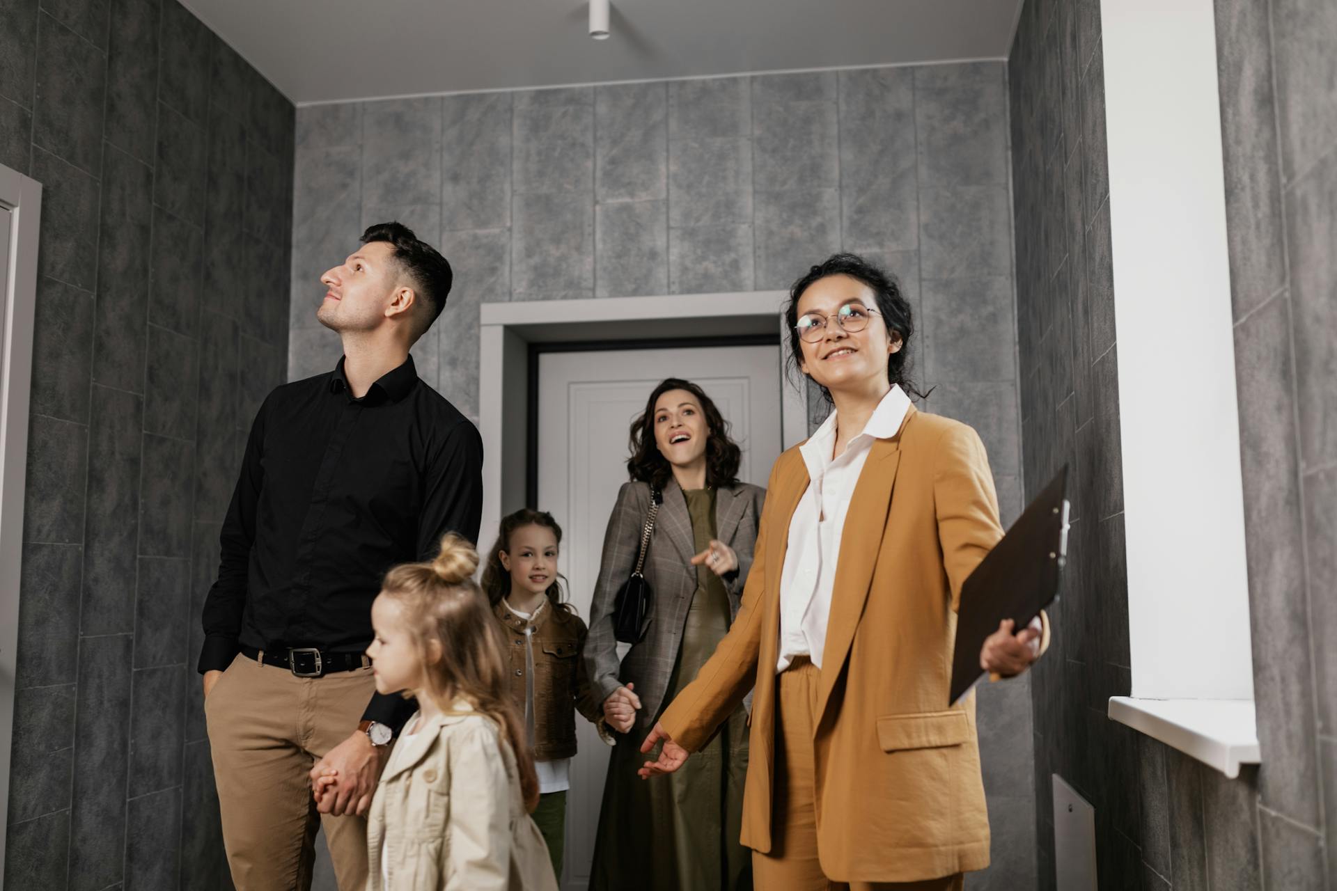 Happy family exploring a new home with a professional real estate agent guiding the tour.