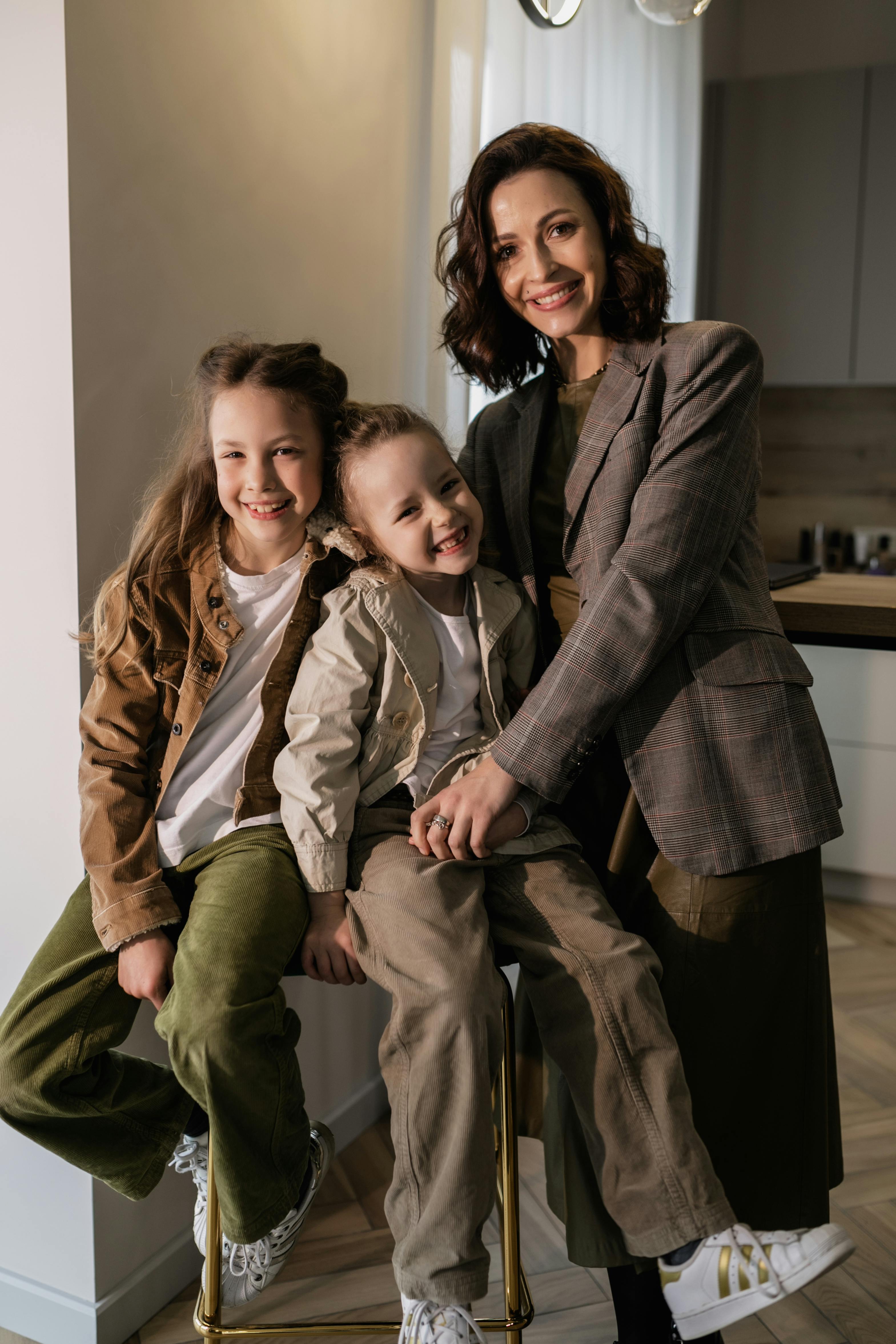 Smiling mother with her daughters in a cozy, modern indoor environment.