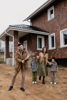 Happy family celebrating new home with champagne outside a brick house.
