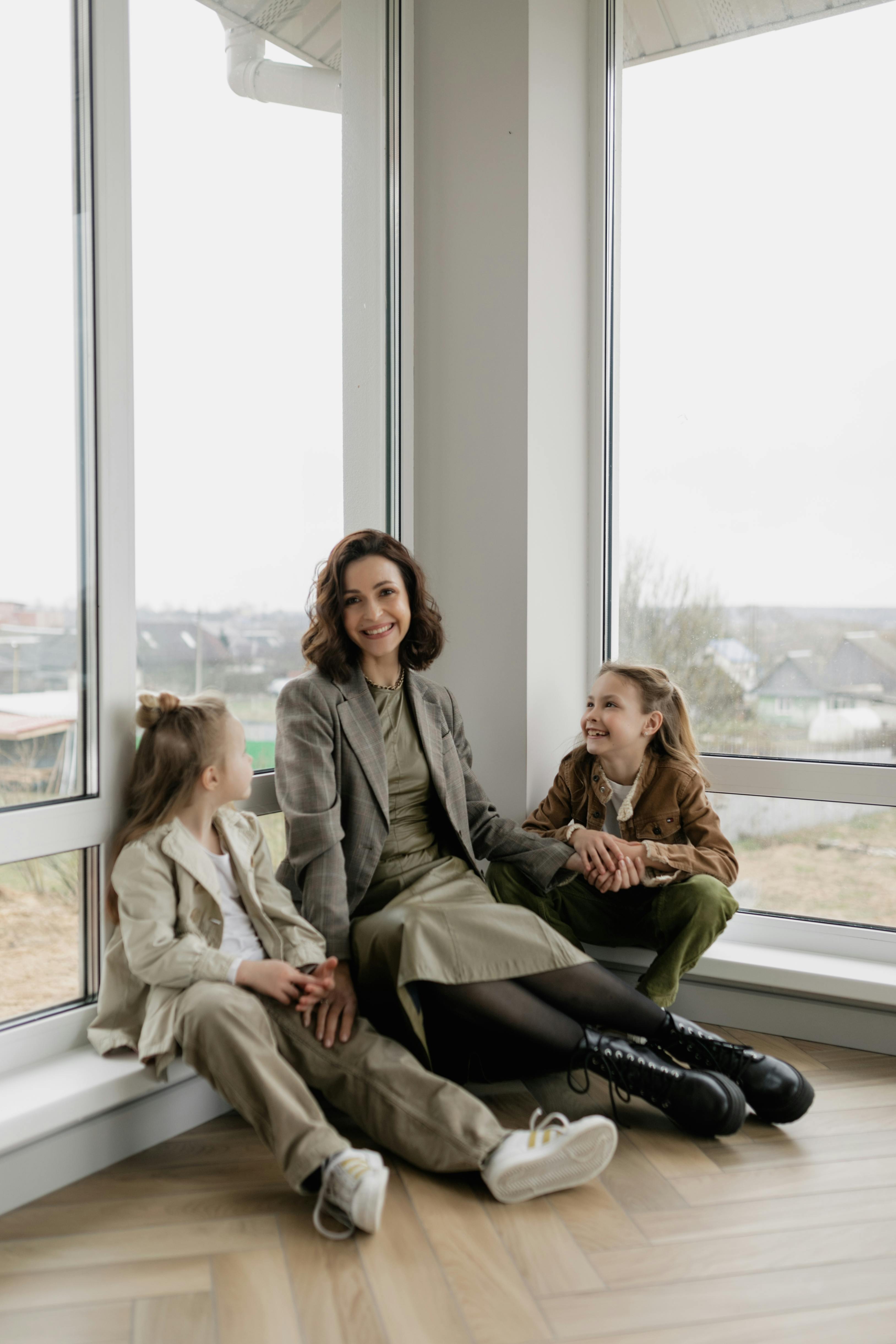 girls and a woman sitting near glass windows