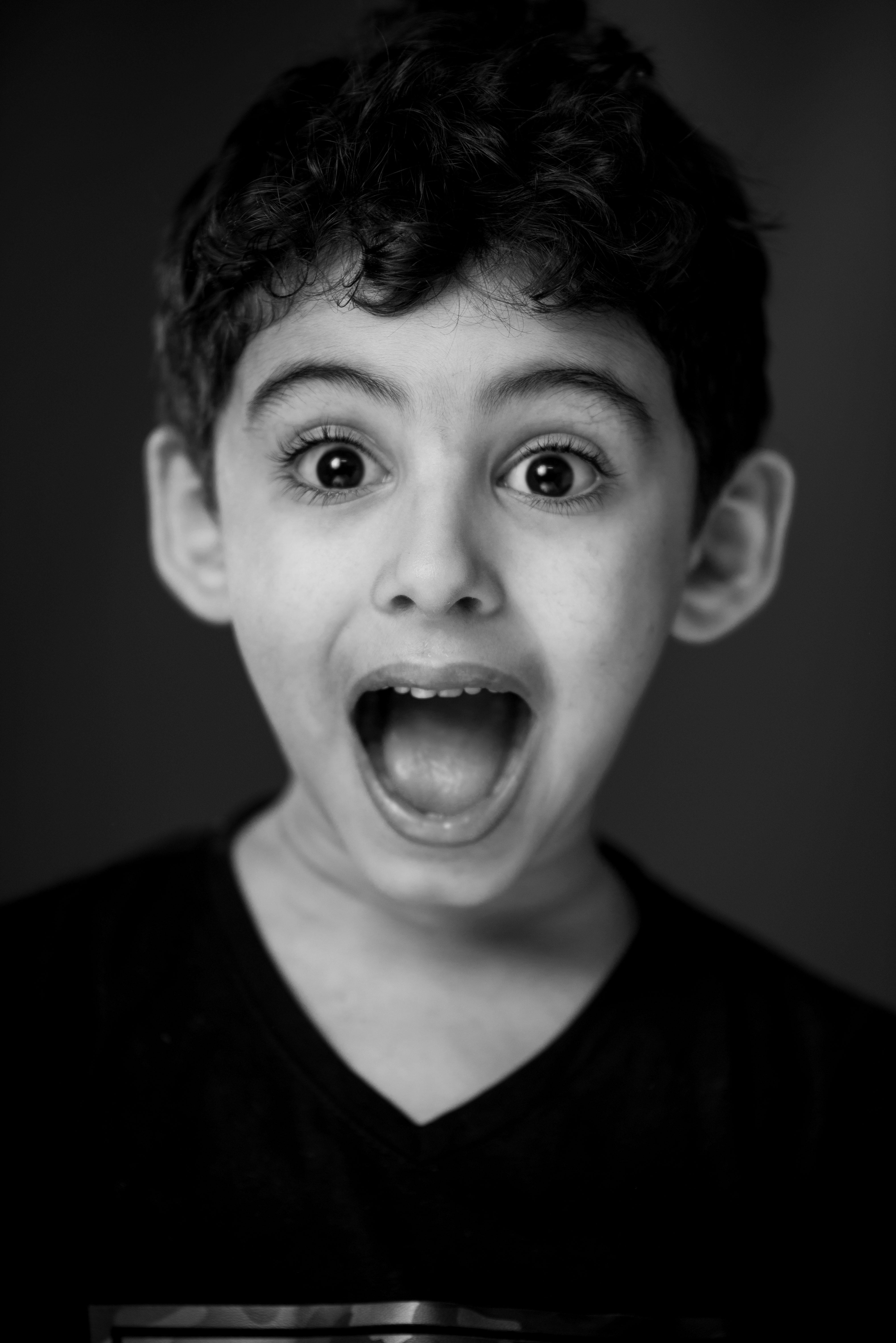 boy in black v neck shirt with looking straight to the camera with a shocking face expression