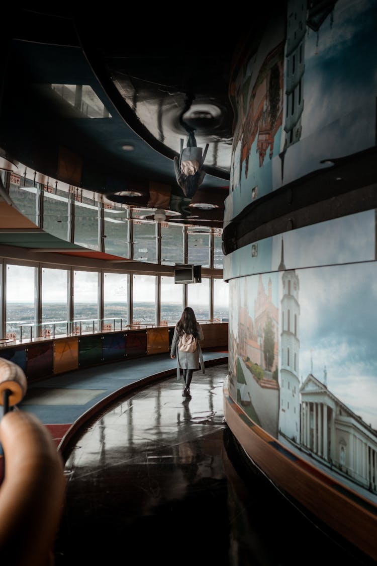 A Person Walking In A Corridor With A Wall Mural