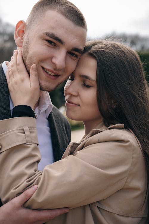 Mindful woman embracing smiling boyfriend on street