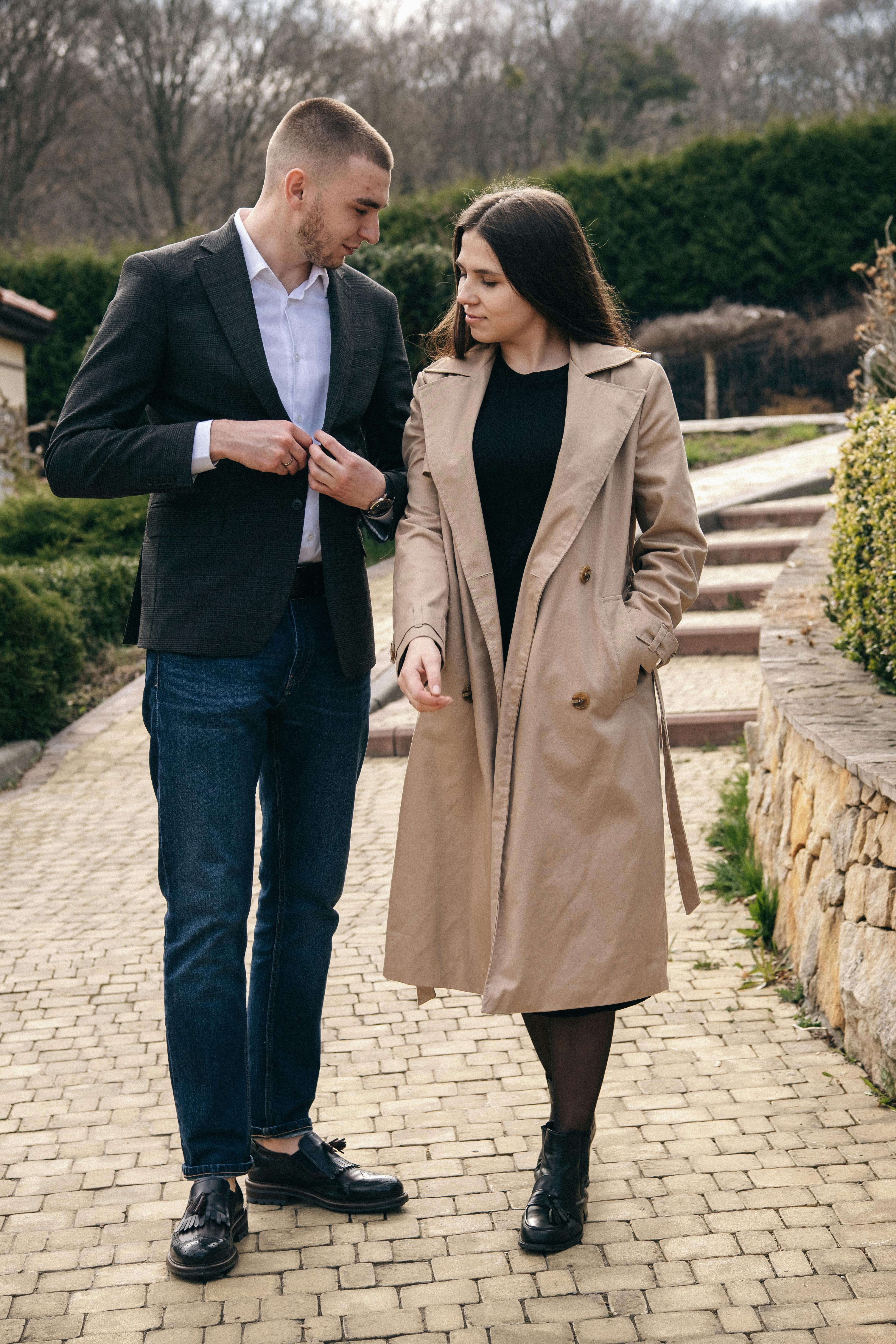 Stylish young man talking to girlfriend with hand in pocket while standing on footpath in park