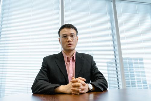 Free Businessman in a suit poised at his desk, exuding leadership in a modern office setting. Stock Photo