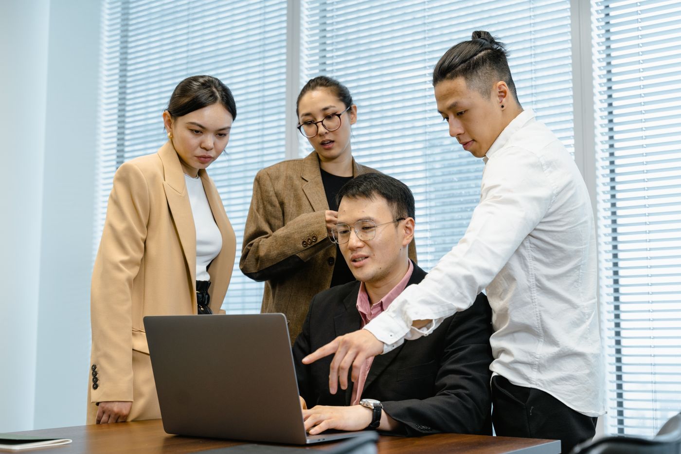 Professionals collaborating around a laptop in an office