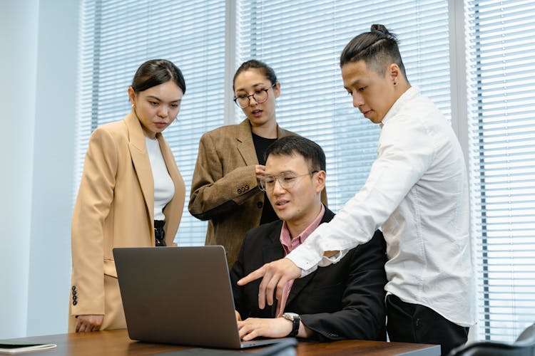 A Team Looking At A Laptop And Collaborating