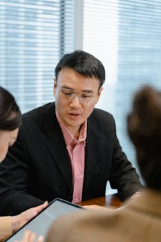 Asian man in a business meeting, discussing ideas inside an office setting.
