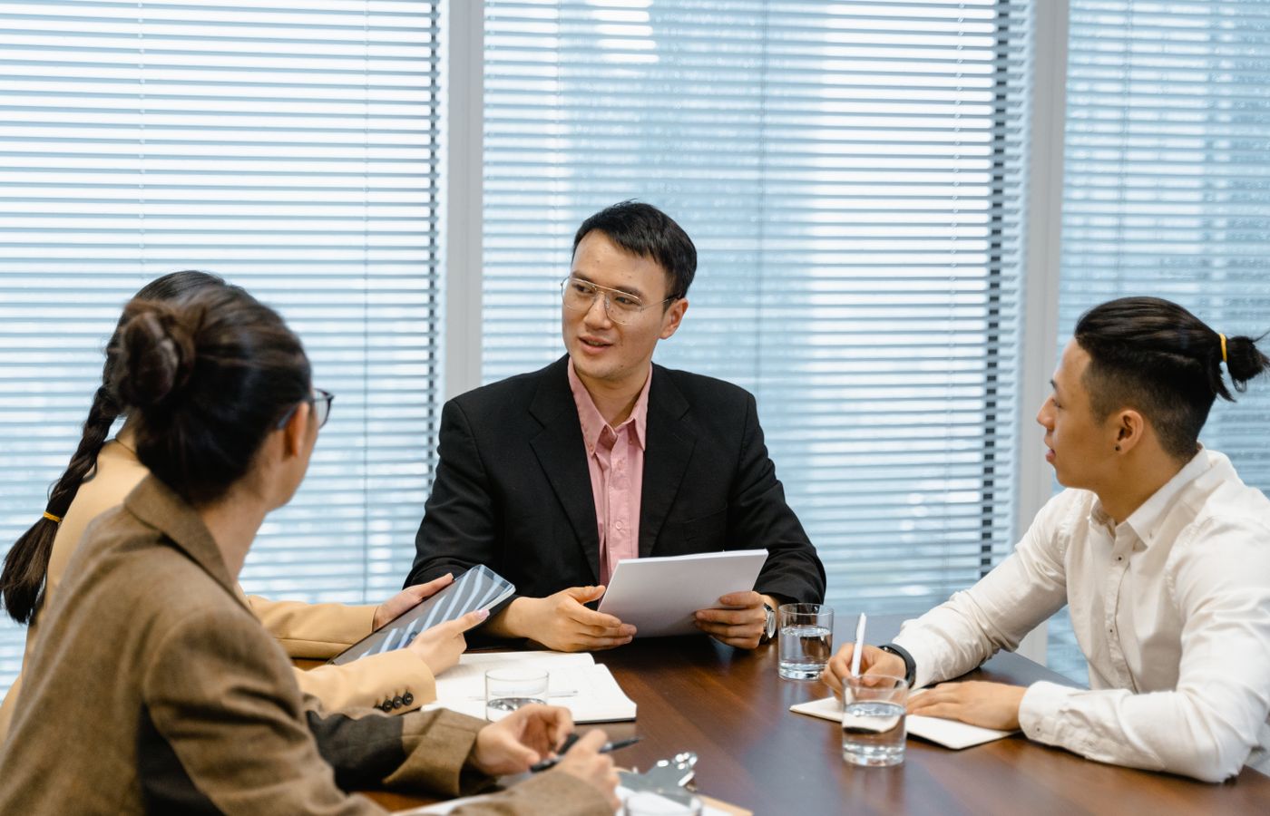 A group of business professionals having a discussion during a meeting in a modern office setting.