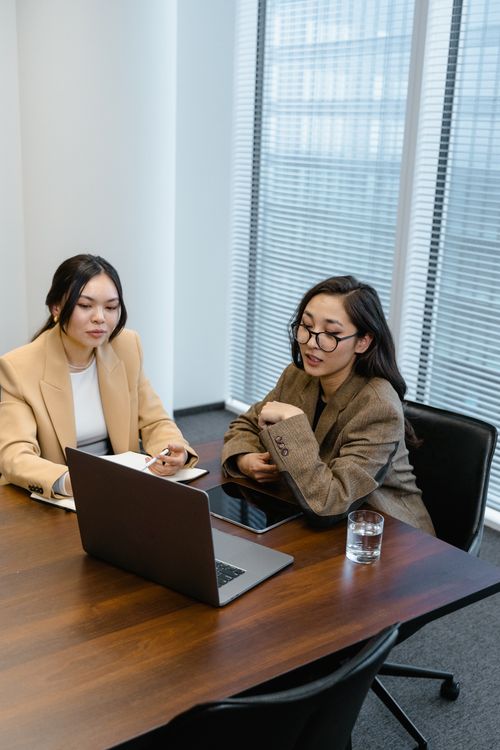 Free Two women in an office engaged in an online business meeting via laptop. Stock Photo