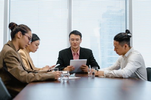 Free Professional business team engaged in a meeting around a conference table in a modern office setting. Stock Photo