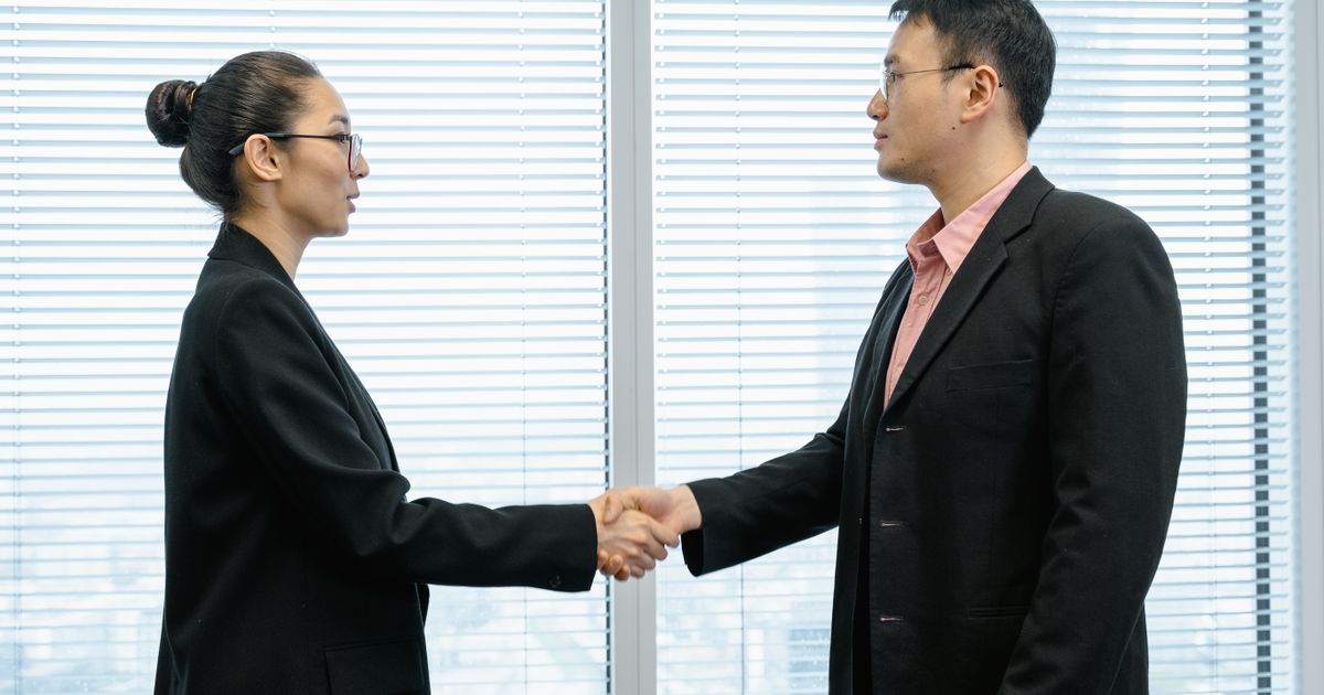 A young professional shaking hands with their new boss in a modern office.