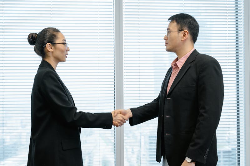 Two business professionals shaking hands in a modern office setting