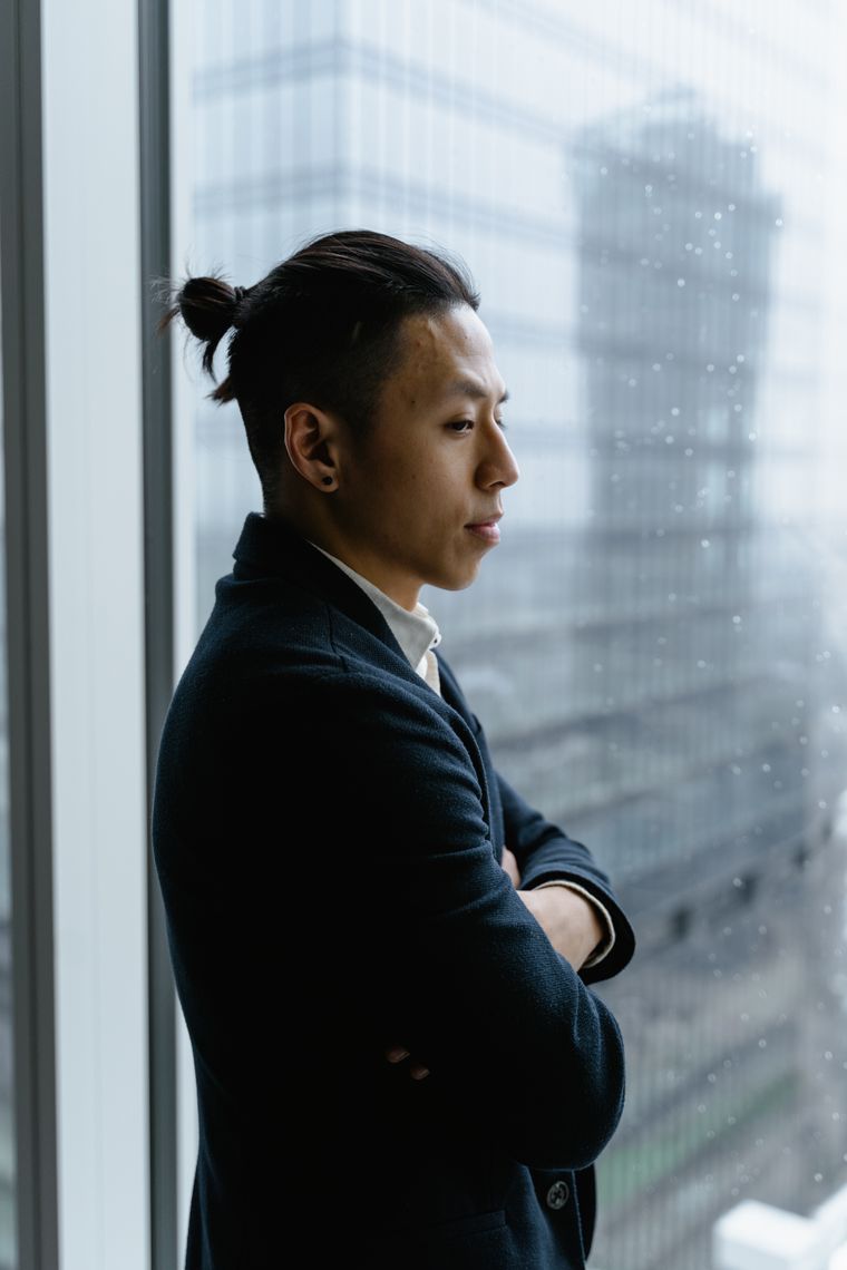 Photo by MART PRODUCTION on Pexels — a research lead standing beside an office window