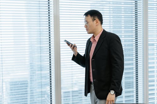 Man in Black Coat Holding a Mobile Phone