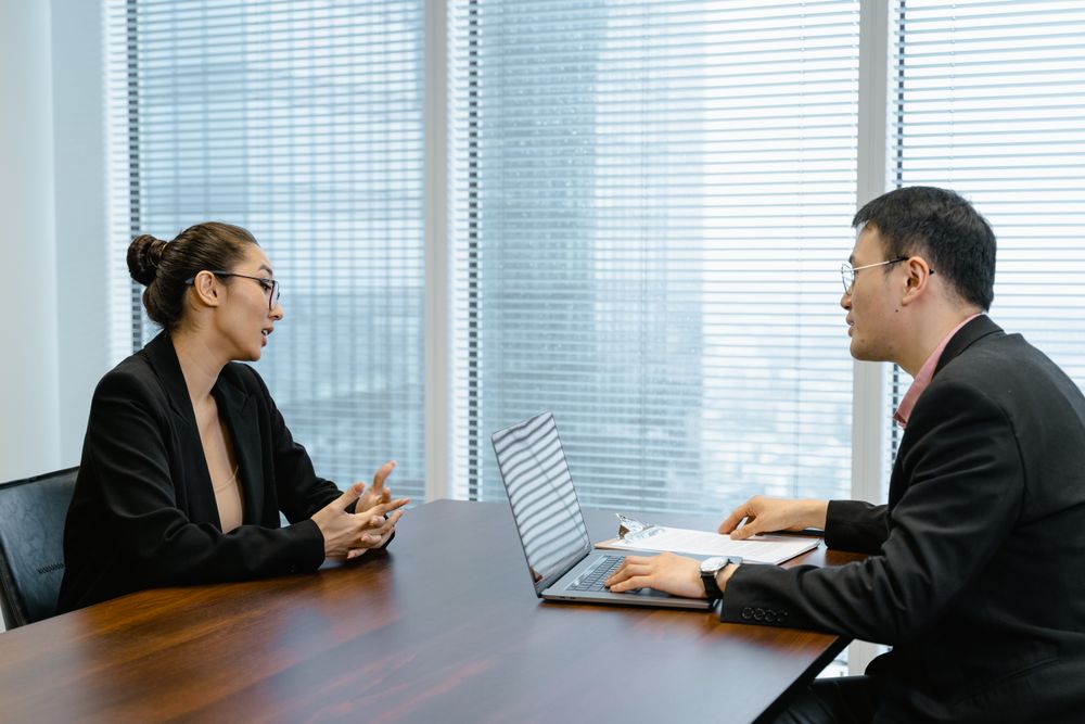 Two product colleagues talking across a desk — photo by MART PRODUCTION on Pexels