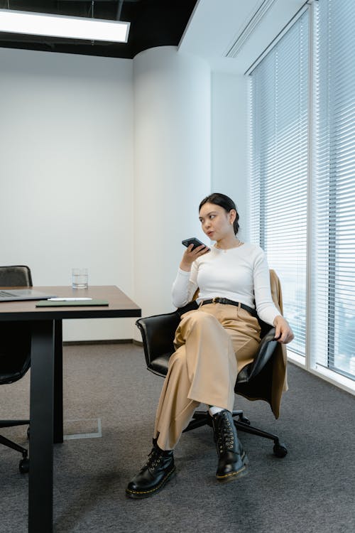 Free Woman Talking on the Phone While Sitting on a Chair Stock Photo