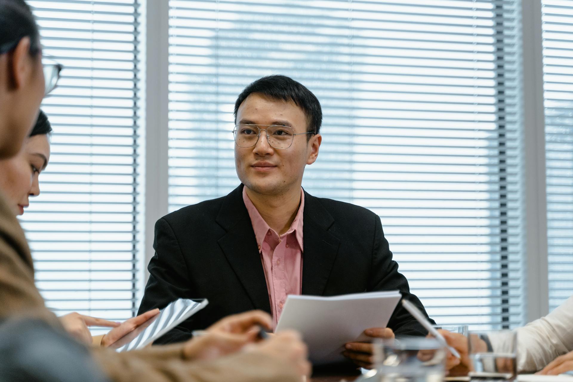 Asian businessman leading a meeting in a modern office setting, fostering collaboration and innovation.