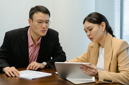 Man and Woman Looking at the Screen of a Tablet