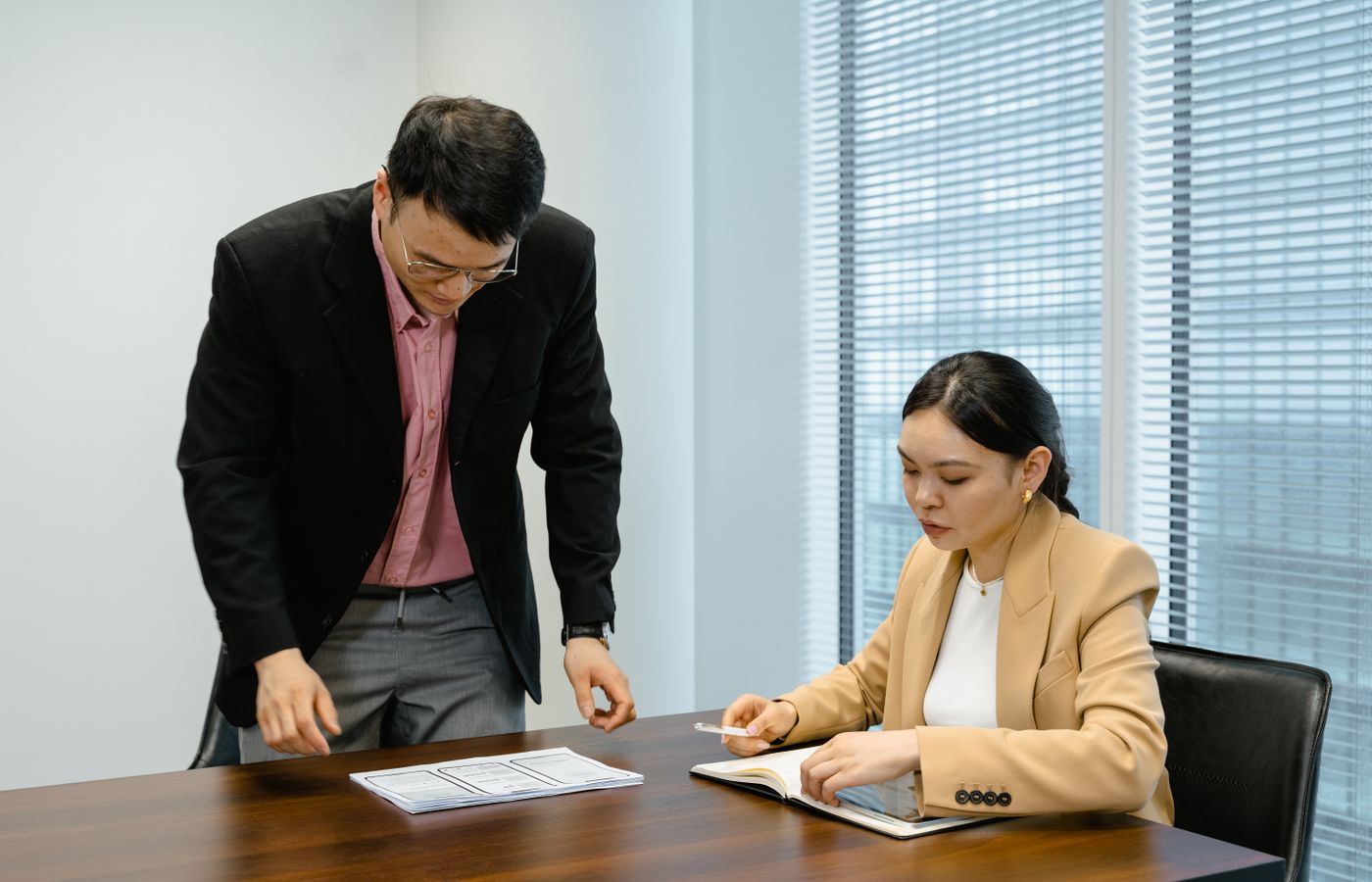 Professional colleagues in a business meeting reviewing documents and taking notes.