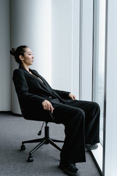 Portrait of a businesswoman seated near a large window, exuding confidence.