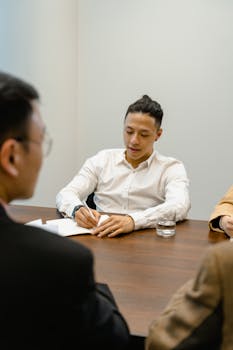 Business professionals in a meeting discussing strategies while taking notes.