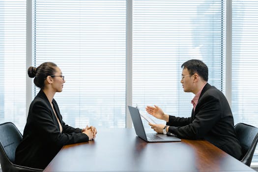 Two businesspeople engaged in a discussion during a professional meeting in an office setting.