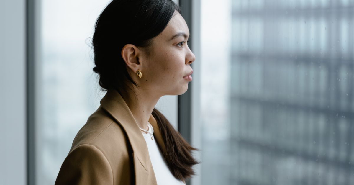 Profile of an Asian woman in a business setting looking thoughtfully out of a window.