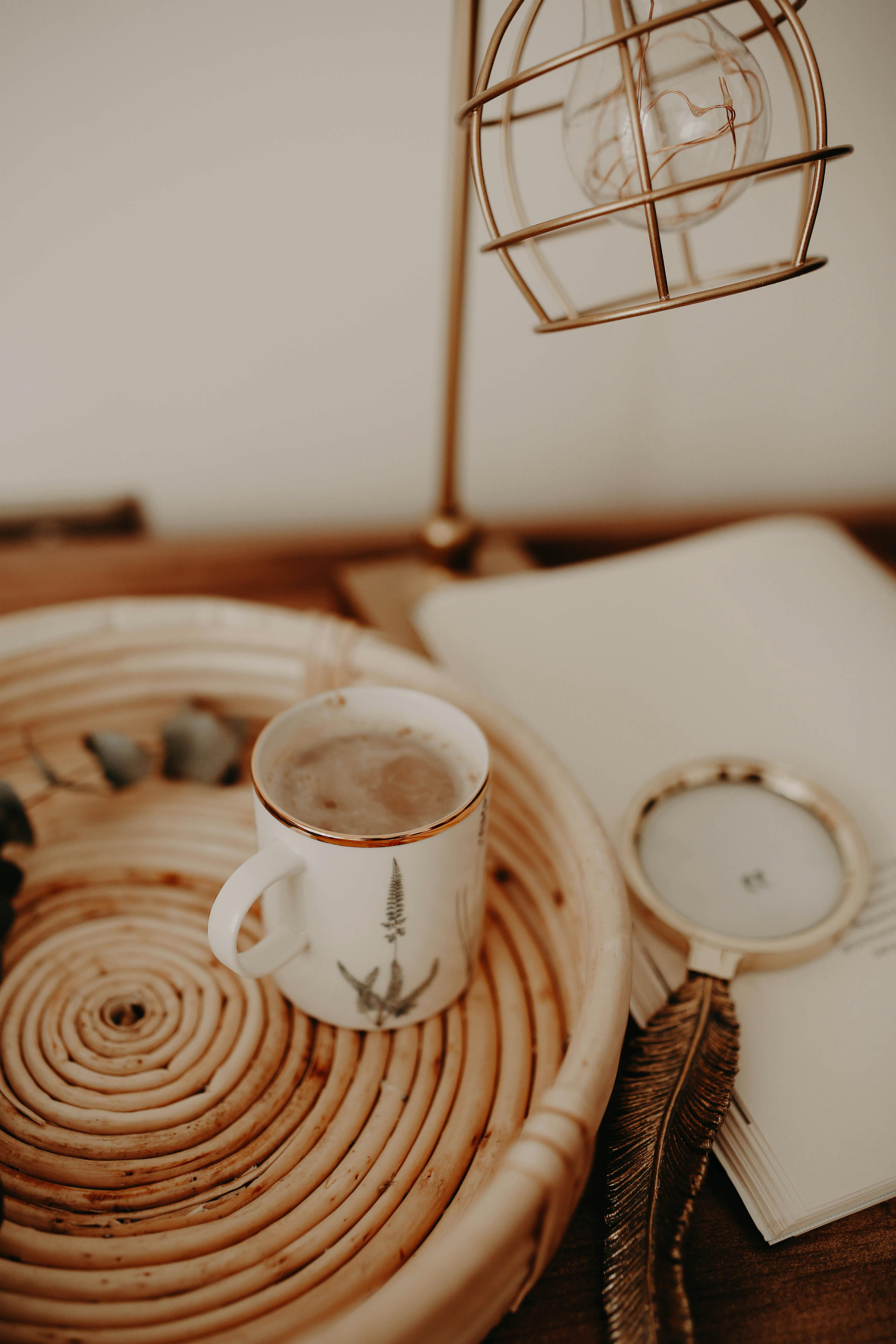 Free Warm and inviting desk scene featuring a coffee mug, magnifying glass, and unique lamp. Stock Photo