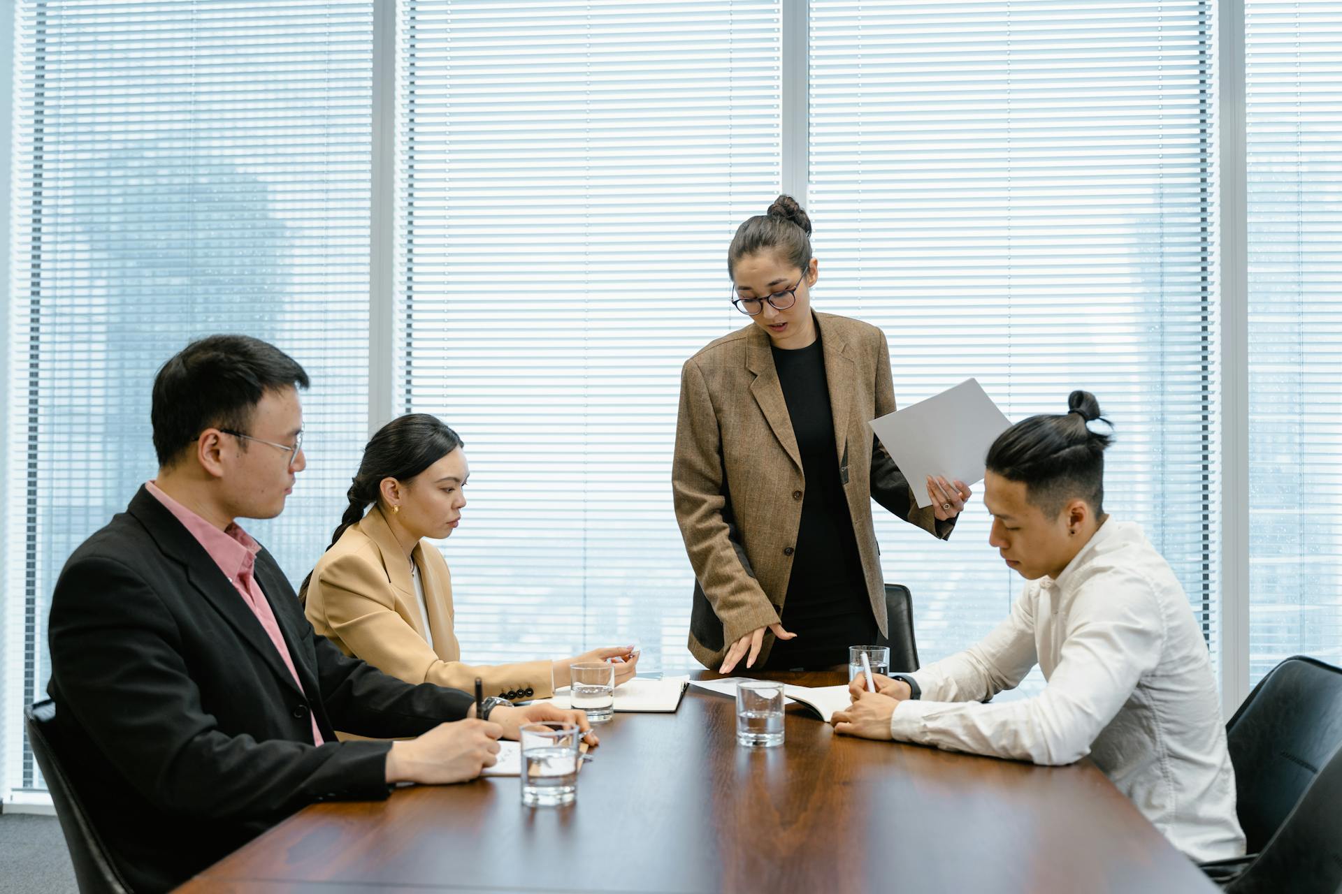 Business colleagues engaged in a meeting around a wooden table within a modern office.