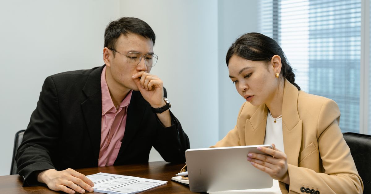 Business colleagues discussing at a meeting with a digital tablet. Indoor setting with focus on collaboration.