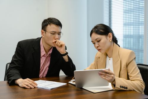 Free Business colleagues discussing at a meeting with a digital tablet. Indoor setting with focus on collaboration. Stock Photo