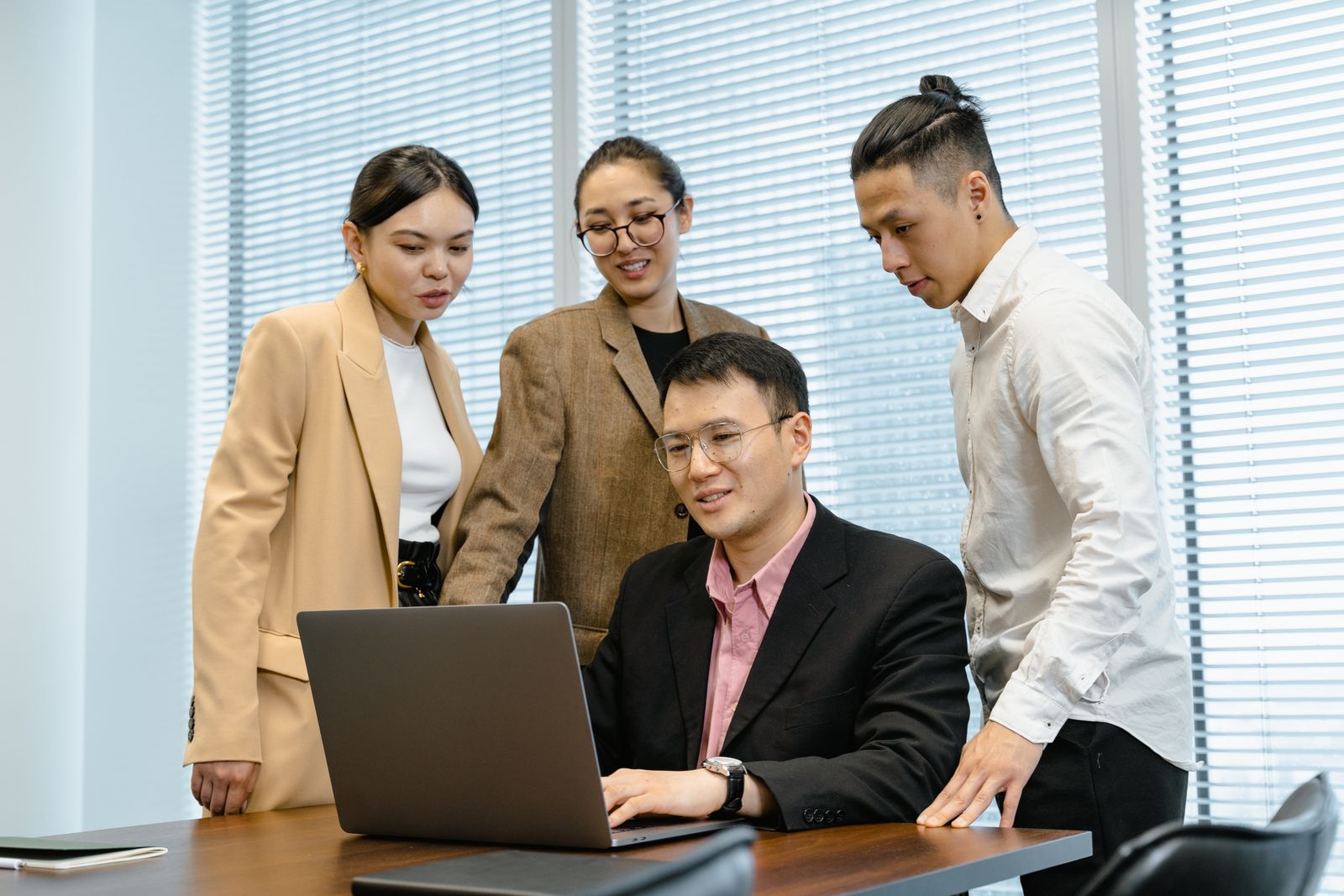 Colleagues gathered around a laptop during a business meeting.