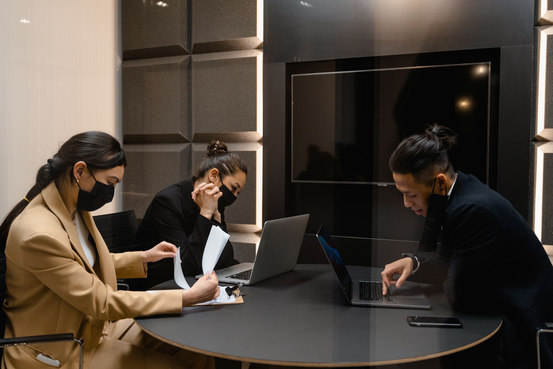 Asian business professionals collaborating in office with laptops and documents during meeting.