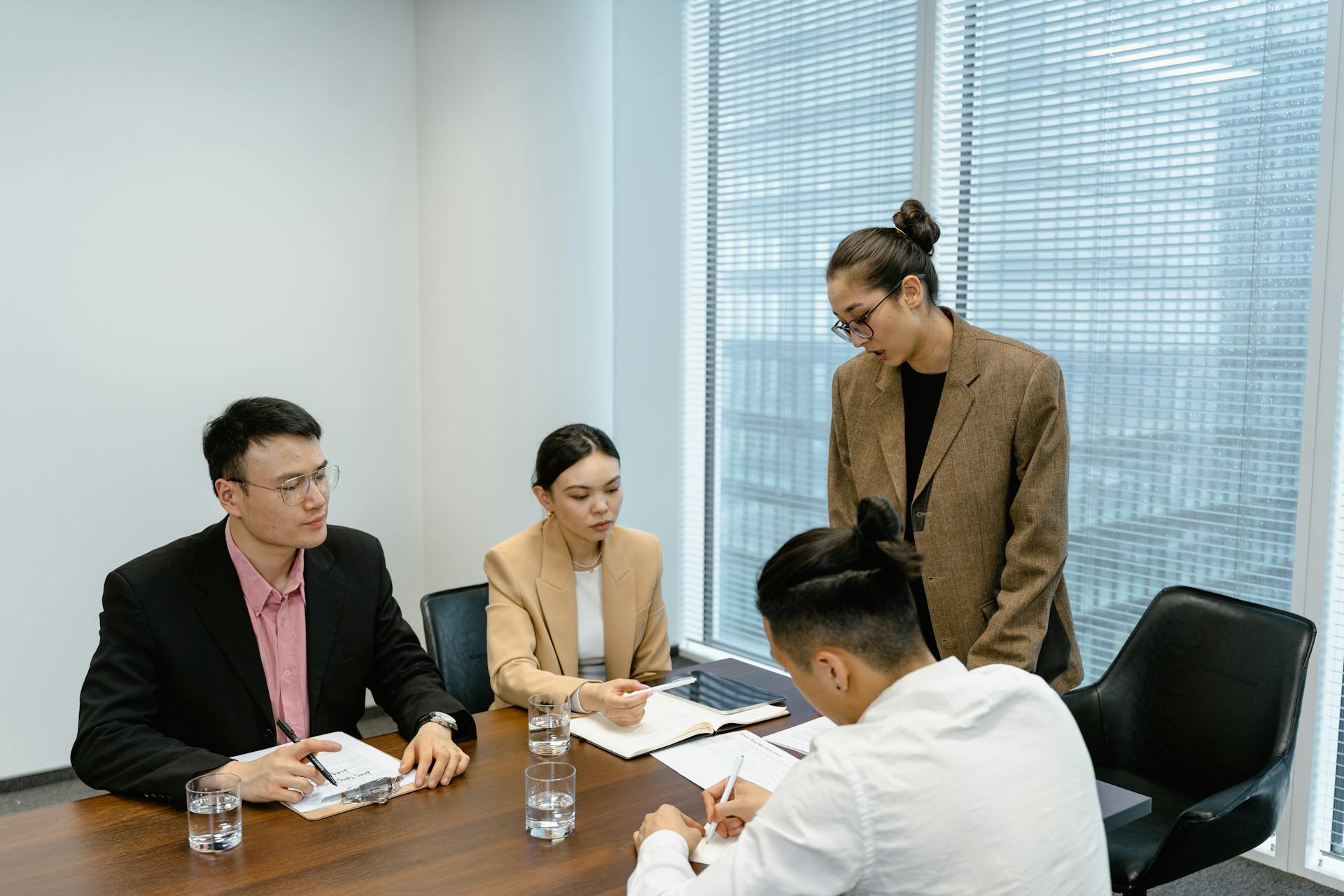 A group of business professionals engaged in a team meeting in a modern office setting.