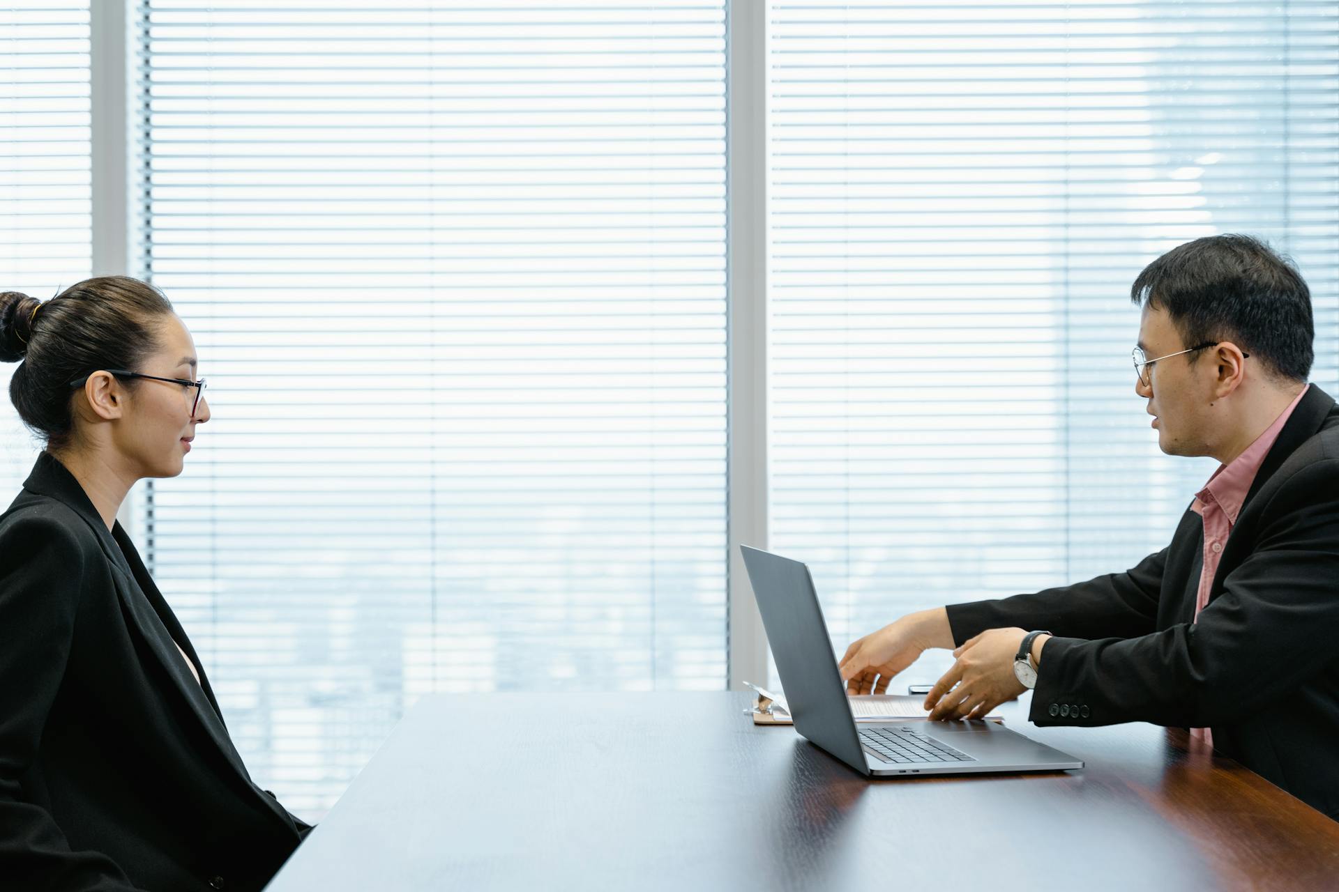 Two professionals engage in a job interview in a modern office. Business attire and corporate environment enhance the scene.