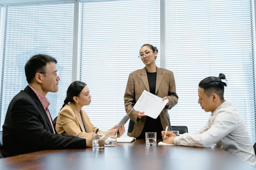 Женщина стоит перед коллегами во время встречи