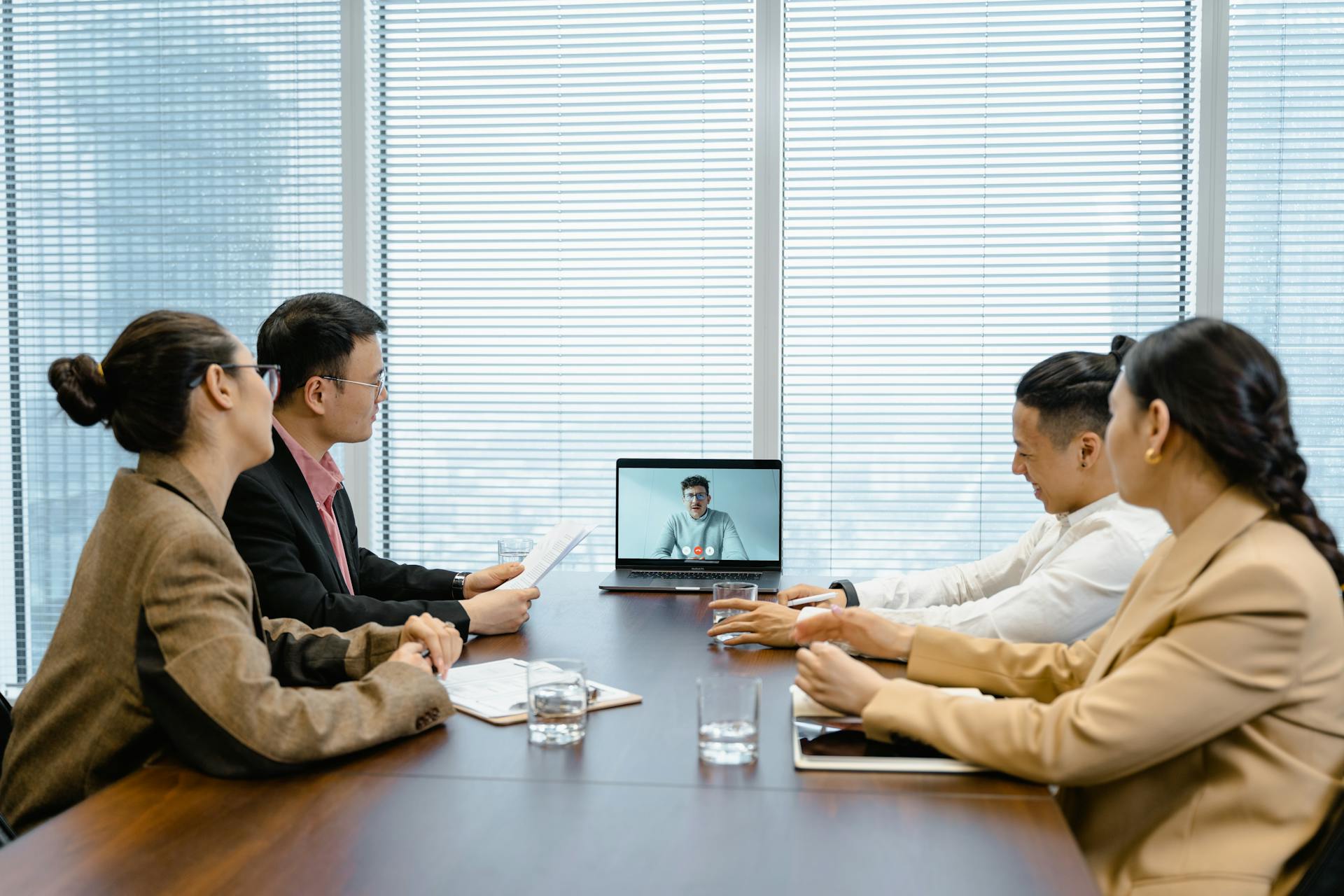 Business meeting with video call setup, highlighting teamwork and communication in a modern office environment.