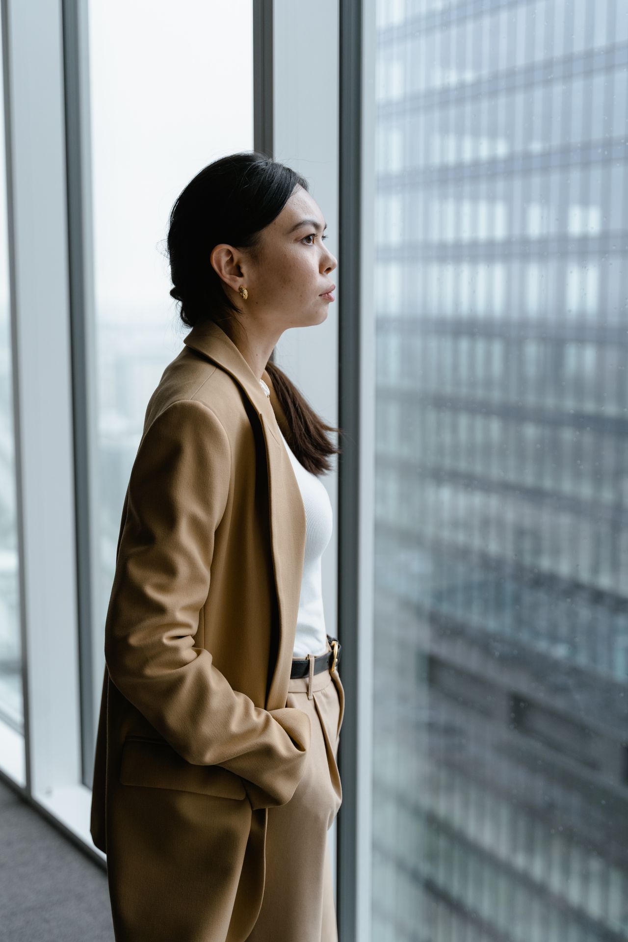 Femme en tenue professionnelle regardant par la fenêtre avec ambition