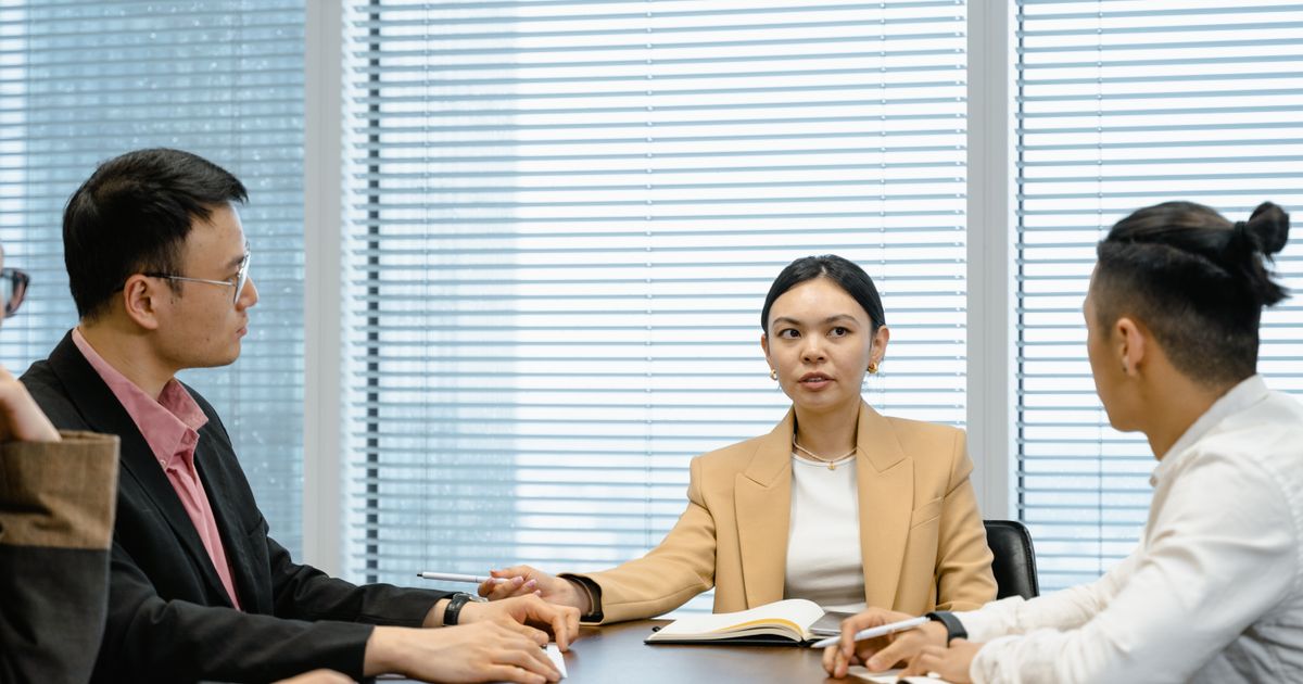 Courtière en discussion avec deux clients autour d’une table de réunion