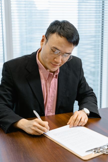 Professional man in business attire signing papers at an office desk. Professional man in business attire signing papers at an office desk.