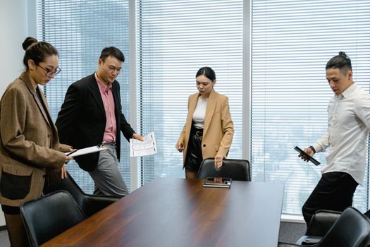 Asian business team having a discussion in a modern office setting.