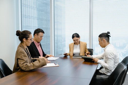 A group of professionals discussing at a wooden table in an office meeting room.