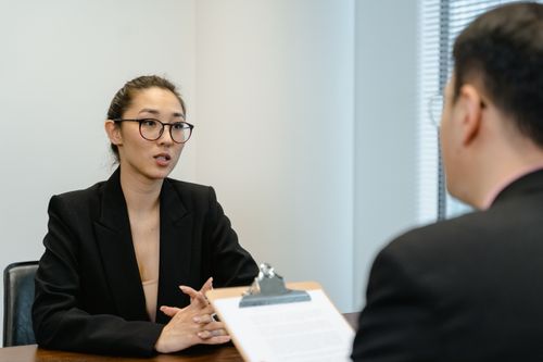 Free A focused interview scene in an office environment with business attire and a clipboard. Stock Photo