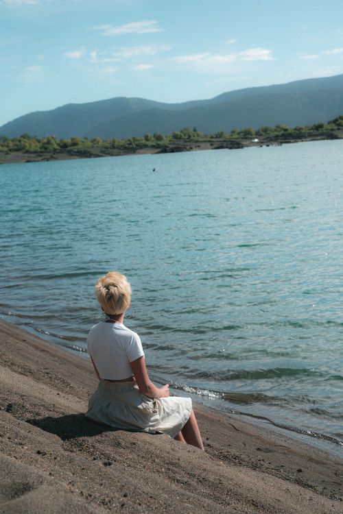 Woman Sitting Near Body of Water · Free Stock Photo