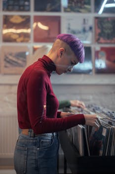 A trendy young woman with vibrant hair browsing vinyl records in a vintage music store.