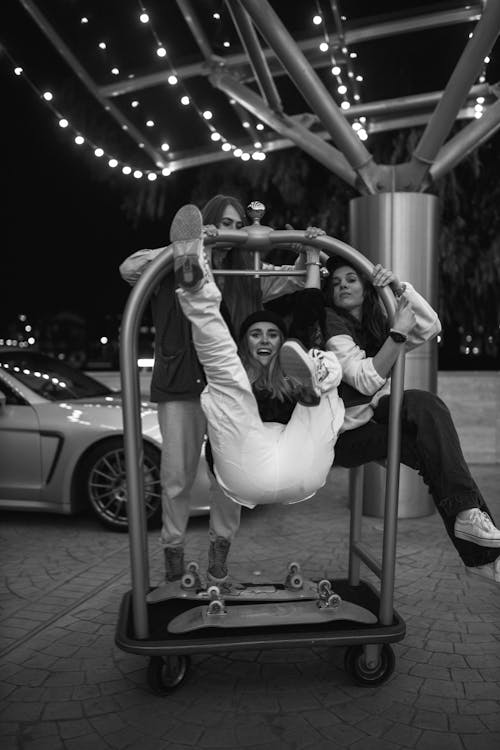 Young Women Hanging from a Luggage Cart