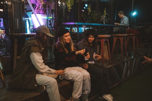 Free Three young women enjoy drinks and friendship at an outdoor bar during the evening. Stock Photo